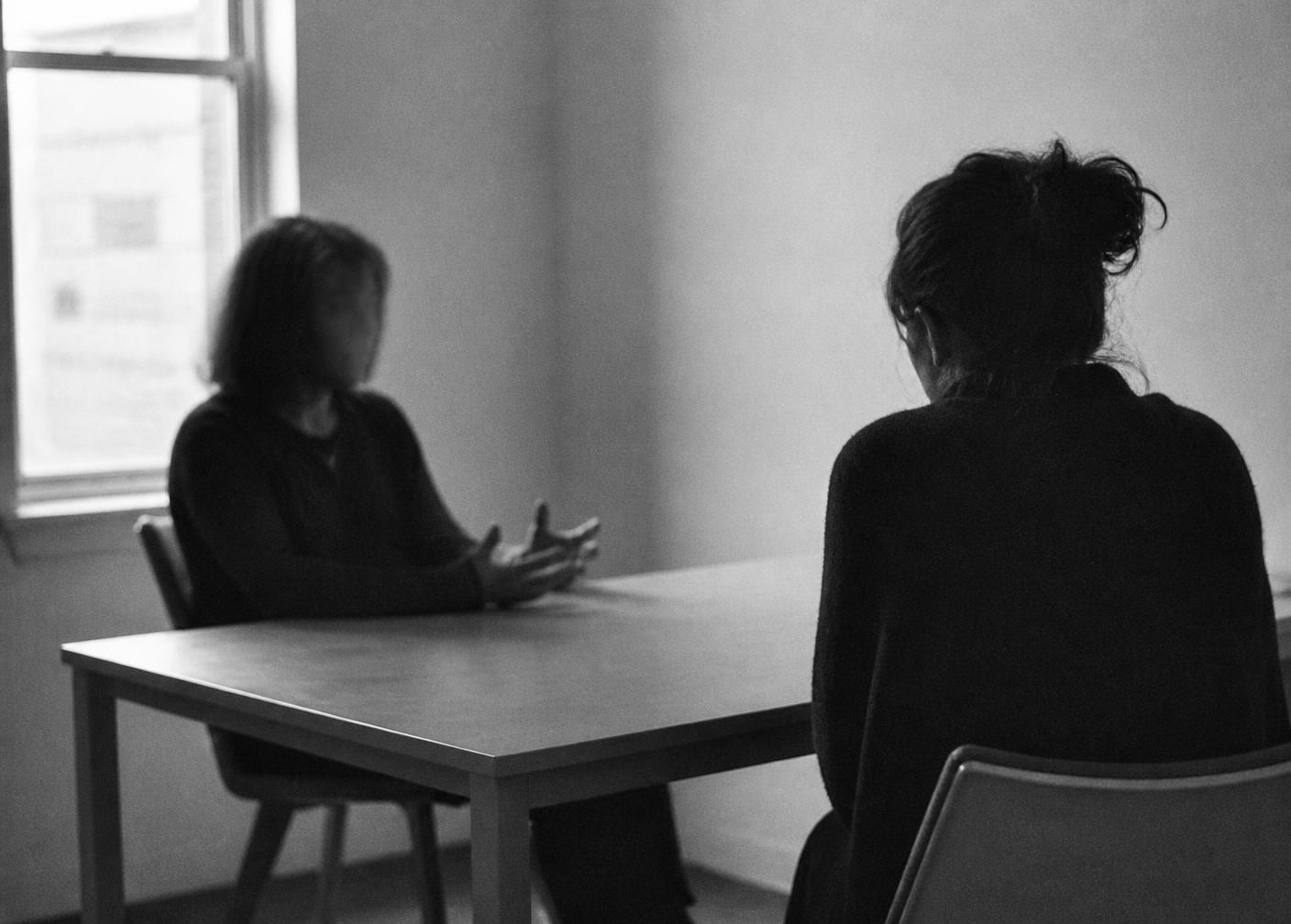 Two people in conversation across a plain table